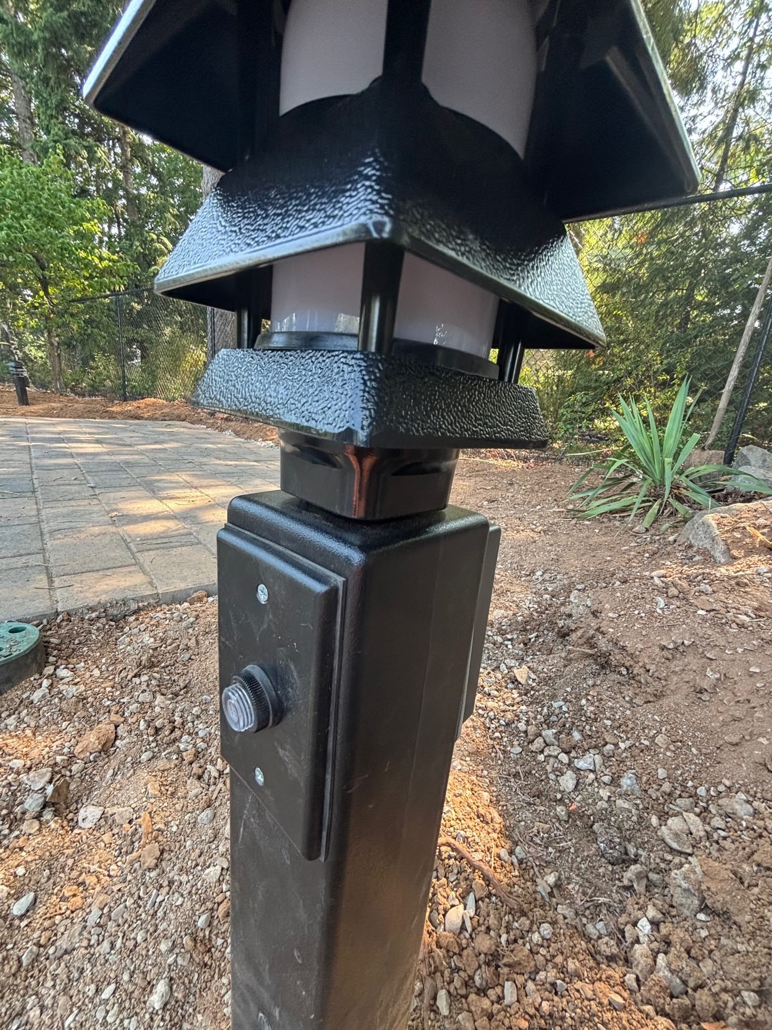 Detail of a landscape light post with a photocell sensor and weatherproof cover plate in an Oregon City, OR yard