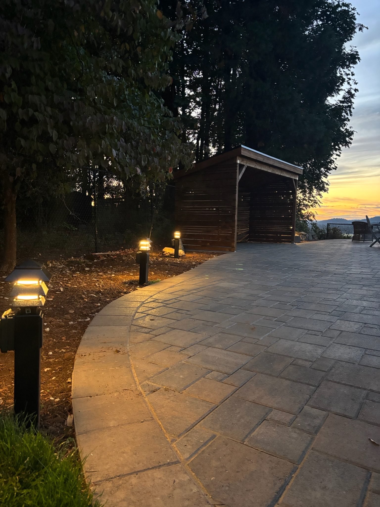 Lit pagoda-style path lights along a curved paver patio at dusk in Oregon City, OR