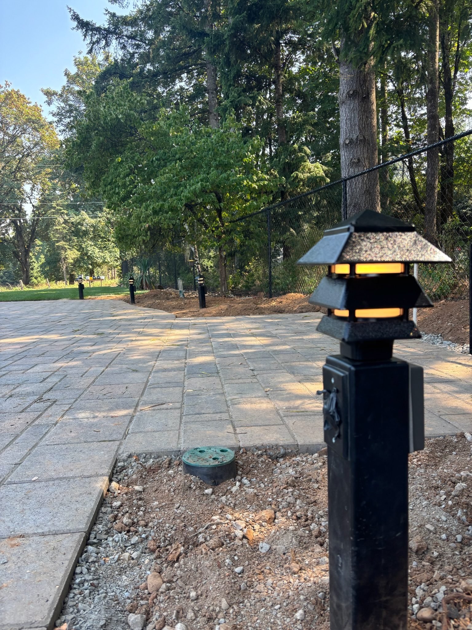 Row of path lights lining a new paver area and planting bed in Oregon City, OR