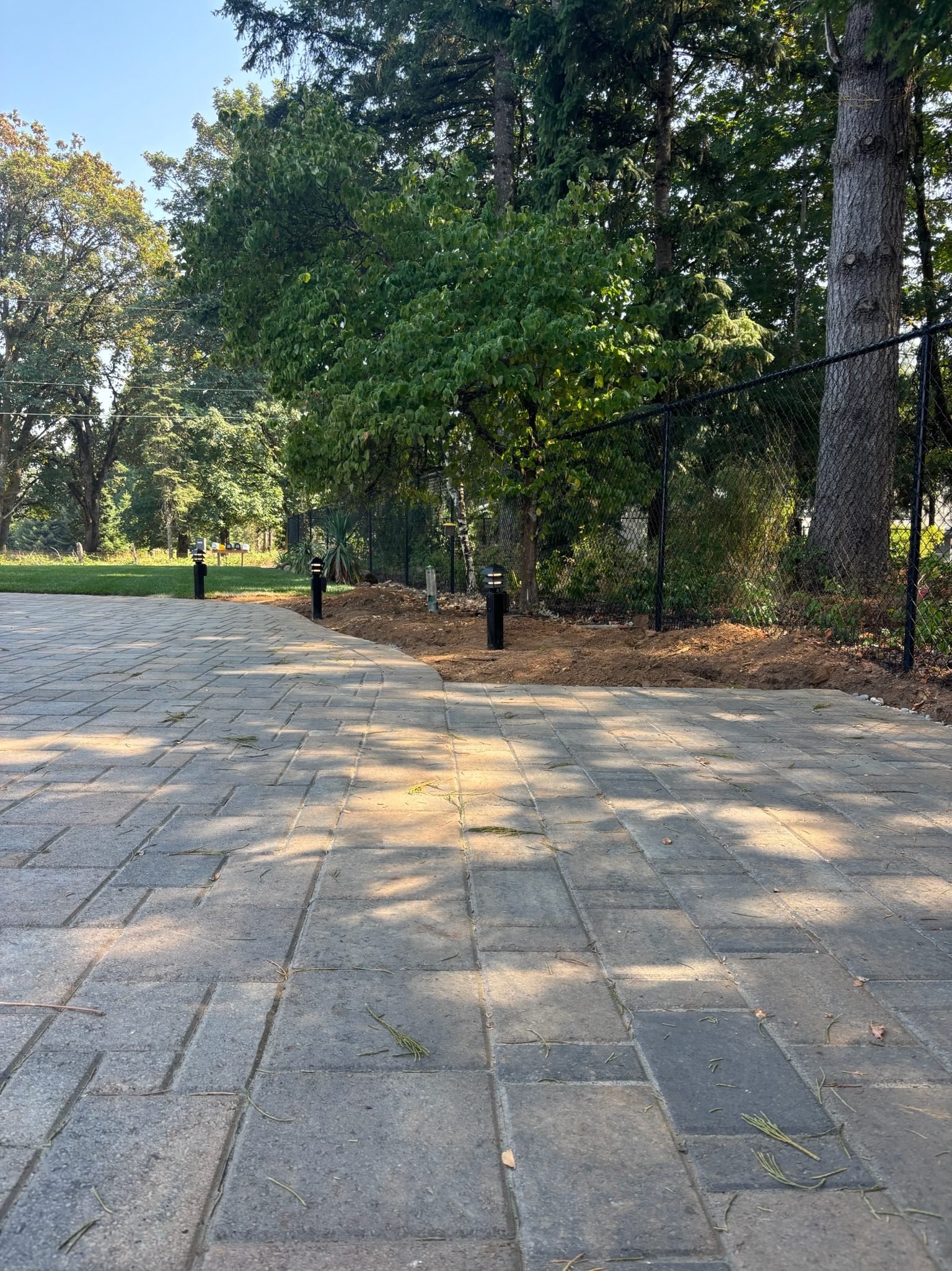 Curved paver patio with landscape path lights along the edge during the day in Oregon City, OR