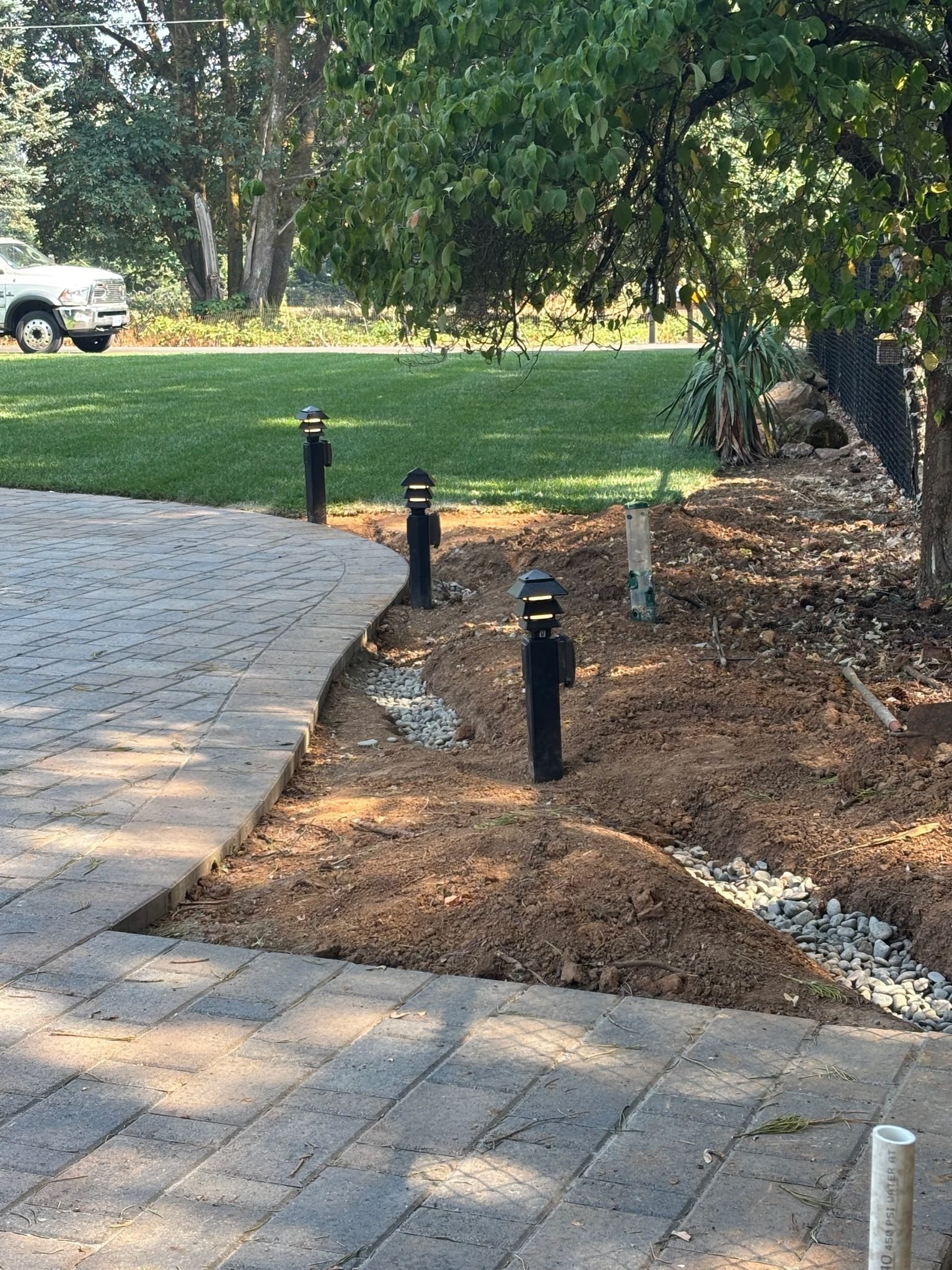 Three installed path lights beside a paver patio in a residential yard in Oregon City, OR